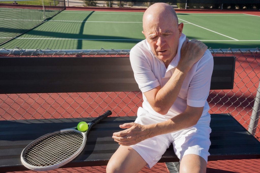man on tennis court with obvious shoulder pain